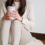 絨毯に座ってコーヒーを持つ女性