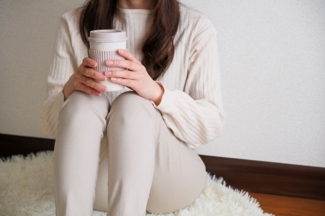 絨毯に座ってコーヒーを持つ女性